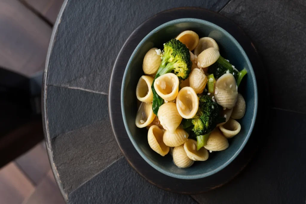 Orecchiette pasta with vegetables on a stone table.